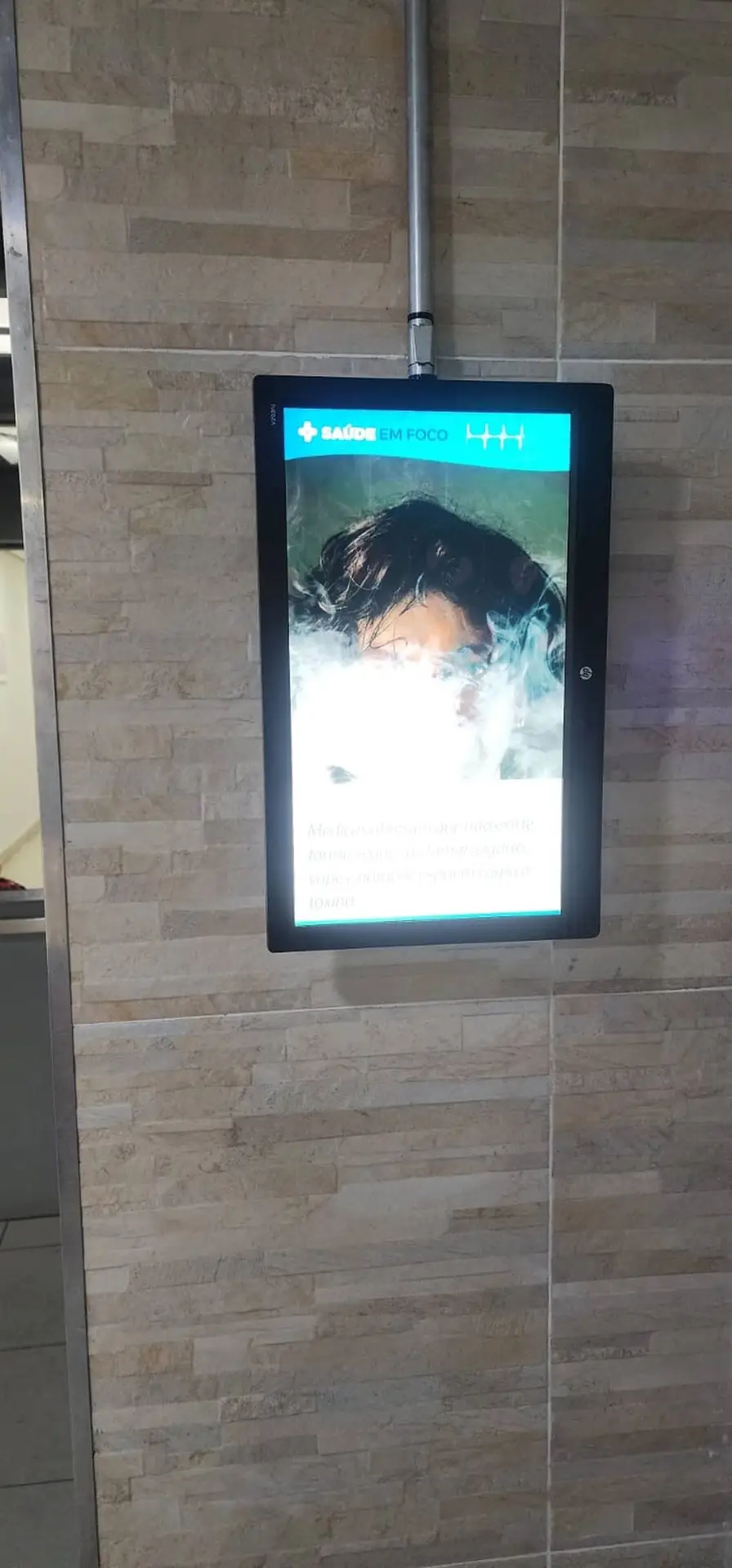 Home Tela digital em Hall de elevador do Condomínio Vida Plena Sabará exibindo campanha Saúde em Foco, destacando dicas de saúde e qualidade de vida.